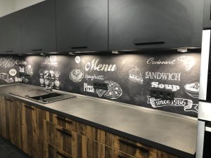 Eine Küche mit dunklen Fronten und einer Schiefer-Rückwand im Dark Kitchen Stil.