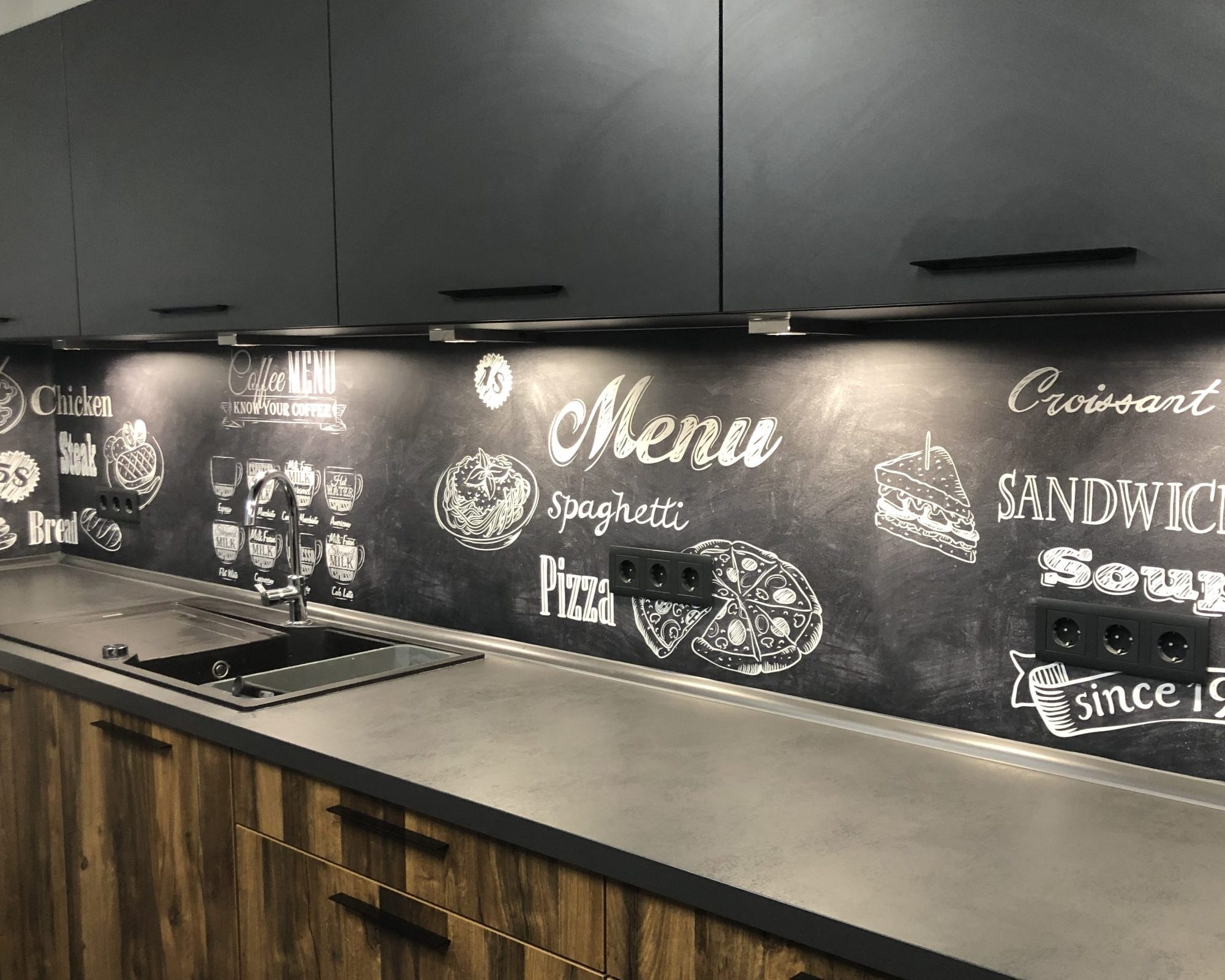 Eine Küche mit dunklen Fronten und einer Schiefer-Rückwand im Dark Kitchen Stil.