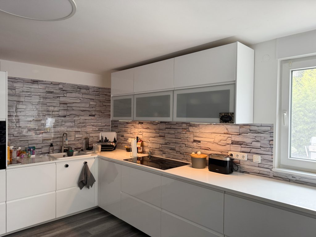 Weiße Küche mit Rückwand in Steinmotivoptik