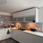 Weiße Küche mit Rückwand in Steinmotivoptik